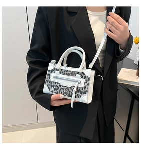 Bolso bandolera blanco con estampado de leopardo combinado con una chaqueta negra elegante