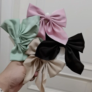 Detail showing four colors of satin bow hair clips in pink, green, black and beige