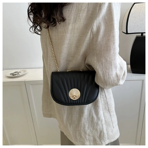 Detail of black plaid saddle bag with golden shell clasp and metal chain on model