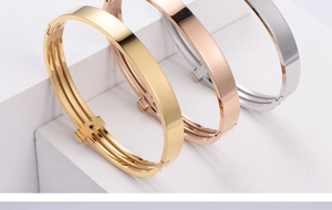 Three-color minimalist steel bangles in gold, rose gold, and silver on white geometric props