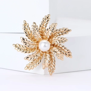 Elegant gold wheat brooch with central pearl inlay on a white minimalist background