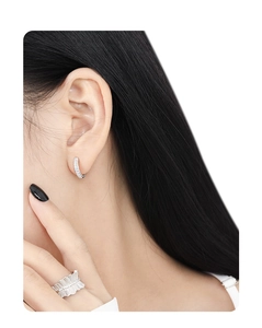 Detailed view of silver micro-pave cubic zirconia earrings and pleated ring on model