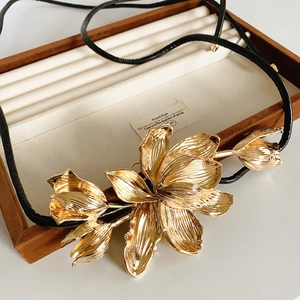 Macro shot of large golden tulip pendant with brushed metal texture on leather cord