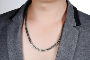 Close-up of a trendy silver titanium steel Cuban link chain necklace worn by a model