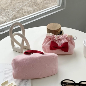 Detailed texture of pink drawstring cosmetic bag with rabbit embossing and red ribbon