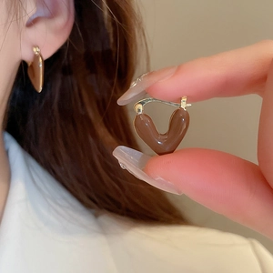 Close-up of caramel brown heart-shaped drop oil earrings with gold metal clasp