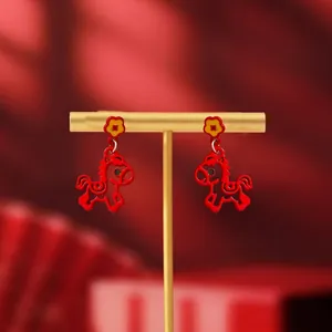 Detail view of 18K gold plated red horse stud earrings on a golden display stand