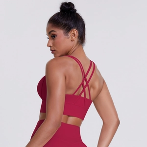 Detail of cross-back straps on dark red sports bra and high-waisted yoga leggings