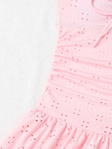 Detailed close-up of light pink eyelet fabric with delicate embroidery and side ruching