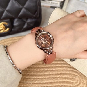 Close-up of rose gold watch with brown leather strap and textured dial on wrist