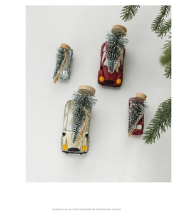 Flat lay of retro Christmas car ornaments with miniature snow-covered trees and pine branch