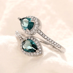 Classic silver bypass ring with two pear-shaped green gemstones and halo diamonds