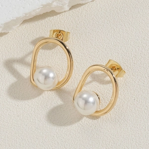 Vue détaillée des boucles d'oreilles dorées en U avec perle sur fond beige minimaliste