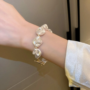 Vue détaillée du bracelet en perles irrégulières avec fermoir en T doré porté par un modèle