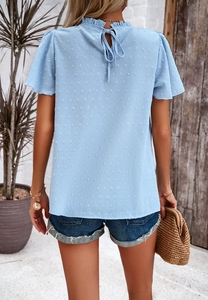Detail view of light blue textured top featuring a high neck and elegant back tie design