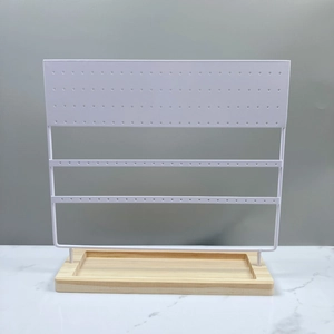 Detail showing white metal 144-hole earring rack with a natural wooden base tray
