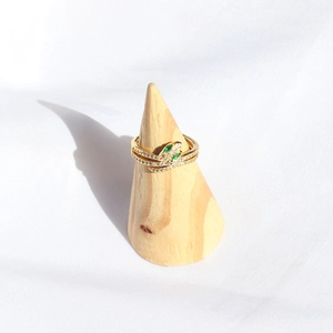 Detail of snake wrap ring in gold finish with white crystals and green stone eyes