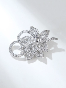 Macro detail of the silver flower brooch back featuring rhinestone inlay and needle pin clasp