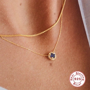 Layered gold S925 sterling silver necklace with a round blue sapphire pendant on a model