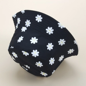 Detail view of daisy embroidery on black cotton bucket hat with white stitching