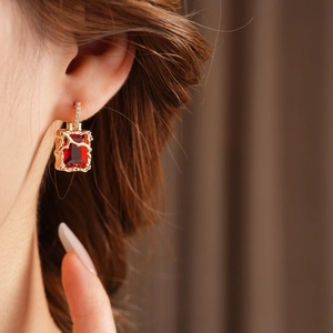 Gros plan sur des boucles d'oreilles vintage en or avec zircon rouge sur un modèle