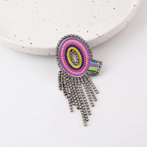 Close-up of colorful crystal brooch with shimmering tassel chains on a ceramic plate