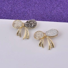Detailed close-up of bow brooches with gold alloy, white crystals and gray druzy stones