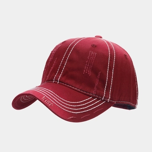 Detail van de wijnrode baseballpet met witte contraststiksels en versleten afwerking