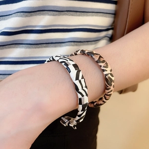 Close-up of leopard print and checkered leather braided wrap bracelets on a wrist
