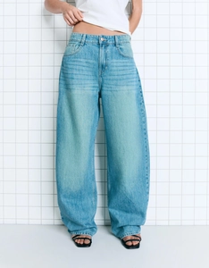 Detail of high-waisted wide-leg jeans in mid-blue wash featuring a retro curved silhouette