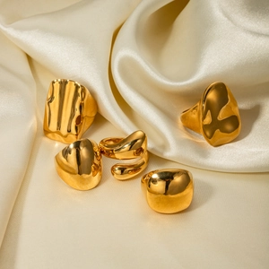 Detail view of five assorted gold-tone stainless steel rings on premium white satin fabric