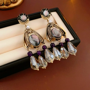 Macro shot of vintage gold earrings with grey gems, purple beads and crystal tassels