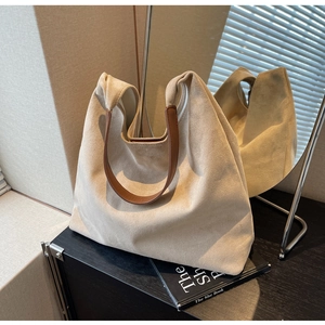 Detail of minimalist faux suede hobo bag with brown leather strap on a decorative book