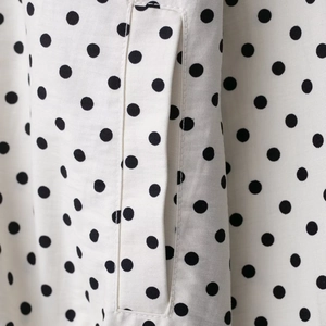 Completo bianco a pois neri con dettaglio di una tasca a filetto di precisione
