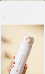 Close-up of matte beige insulated bottle with orange safety lock and spring lid