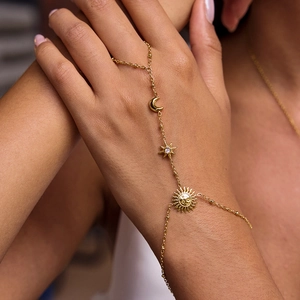 Macro view of 18K gold plated hand chain featuring sun moon and star charms with crystals
