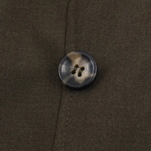 Detail of high-quality dark olive fabric with shoulder pad seam and textured resin button