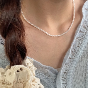 Detail of elegant white pearl bead necklace worn on neck with lace cardigan background