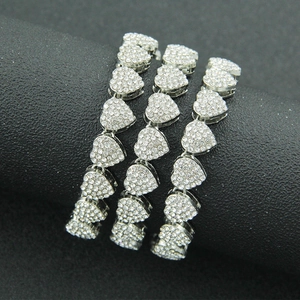 Close-up of three silver iced-out heart link bracelets on a black cylindrical stand