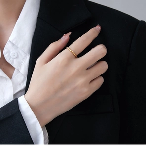 Detail of a thin gold honeycomb ring worn with a professional black and white outfit