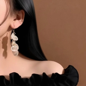 Detail of round shell tassel earrings worn by model for a trendy summer beach vacation look