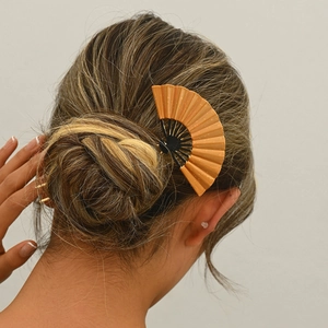 Close-up of a gold folding fan hair pin styled on an elegant bun for a traditional look