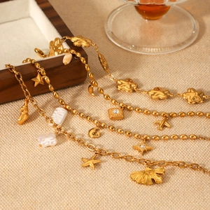 Close-up of four gold bracelets with star, moon, and shell charms on a wooden tray