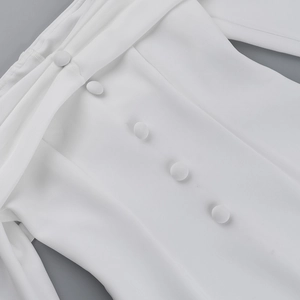 Detailed view of white off-shoulder dress featuring delicate fabric-covered buttons