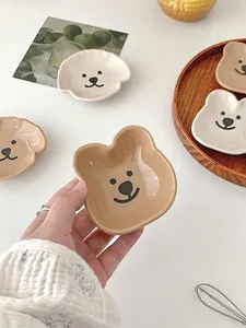 Close-up of cute bear-shaped ceramic sauce dishes in beige and white glossy finish