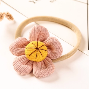 Detailed macro view of pink corduroy daisy flower hair tie for children on card