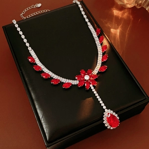Detail of red flower pendant and teardrop gemstone on silver necklace in a black box