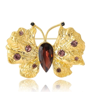 Elegant gold butterfly brooch with deep red teardrop gem and purple stones on white background