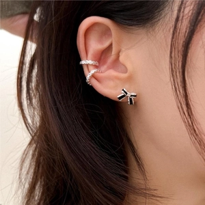 Close-up of model wearing black bow stud earring and silver zircon ear cuffs