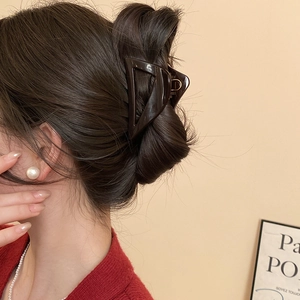 Detail view of large brown triangle hair claw clip on model with elegant styling